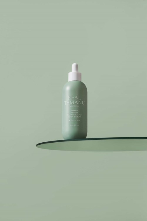 Eine grüne Hautpflegeflasche mit Pipette steht auf einem passenden grünen Hintergrund und wirft einen Schatten.