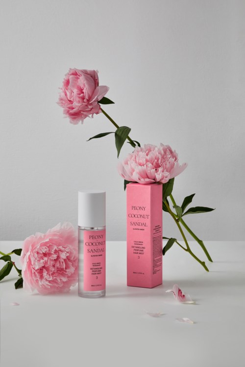 Ein Hautpflegeprodukt mit pinken Blumen und einer pinken Verpackung, arrangiert vor einfachem Hintergrund.