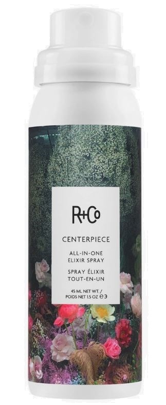 En vit sprayflaska med ett färgstarkt blomstermotiv, märkt R+Co Centerpiece All-in-One Elixir Spray.