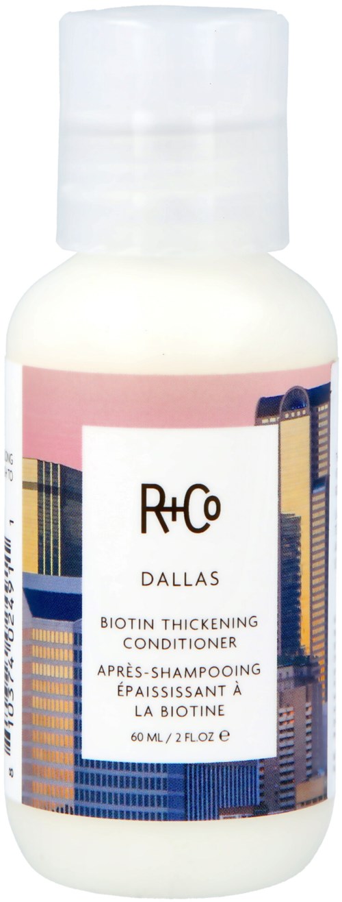 A small white bottle with a pink and city building design label, containing a hair conditioner for strengthening hair.