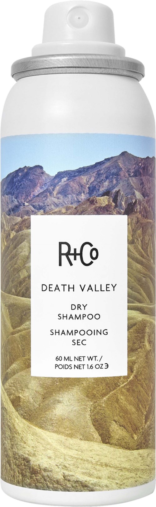 En hvit sprayflaske med fjellandskap på etiketten, merket 'R+Co Death Valley Dry Shampoo' med 60 ml innhold.