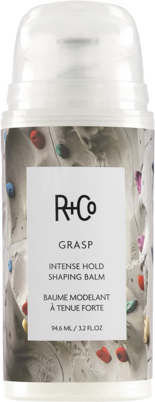 Eine weiße Flasche von R+Co Grasp Styling-Balm mit bunten Klettergriffen auf dem Etikett.