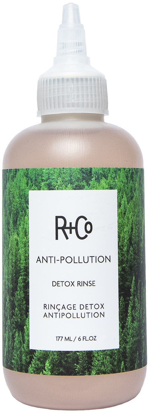 En beige flaska med grönt skogstema etikett för R+Co Anti-Pollution Detox Rinse, 177 ml, med vitt spraylock.