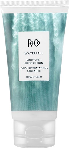 En tub med R+Co Waterfall Moisture Shine Lotion med vattenstänk i bakgrunden.