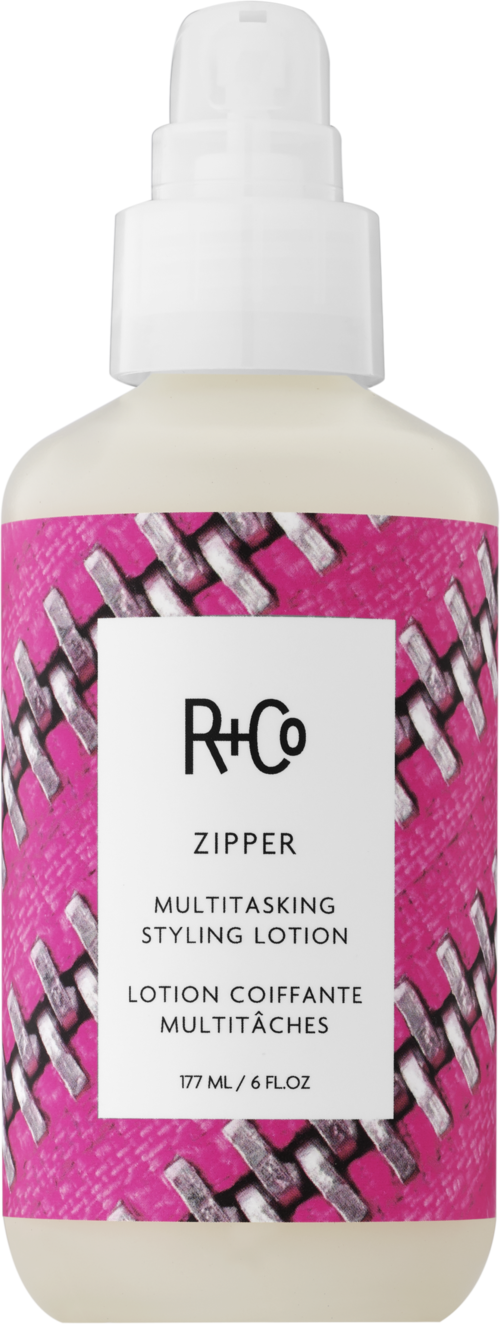 Eine weiße Sprühflasche mit pinkem Etikett im Reißverschluss-Design und Text 'R+Co Zipper Multitasking Styling Lotion.'