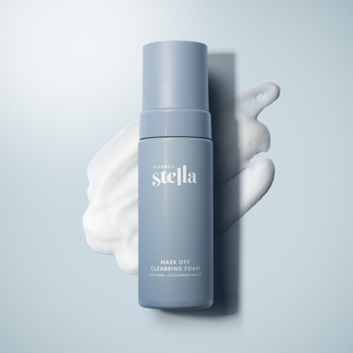 A blue bottle of cleansing foam with white foam next to it on a light background.