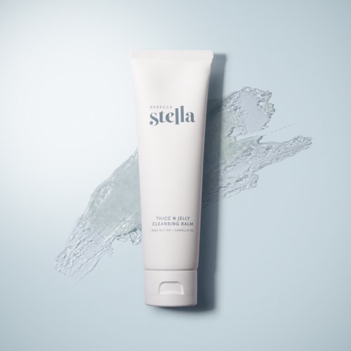 En vit tub med texten 'stella', med vattenstänk bakom, på en ljus bakgrund.