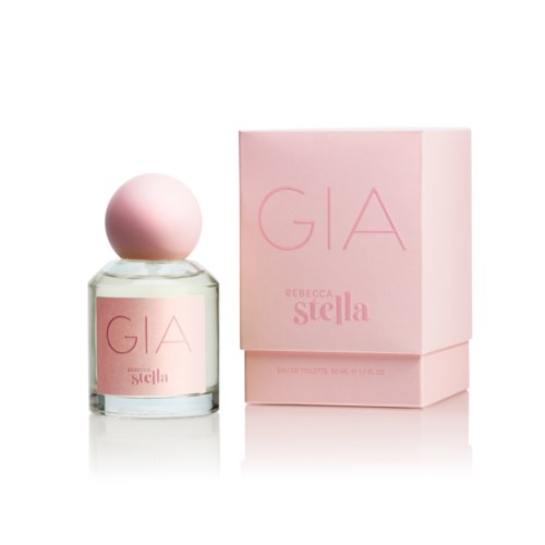 En parfymeflaske med rosa etikett og rund rosa lokk, ved siden av en rosa eske med ordene "GIA REBECCA Stella."