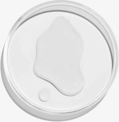 Ett klart runt behållare med ett vitt gelé och en liten droppe inuti. Gelen är ojämnt spridd inuti behållaren.