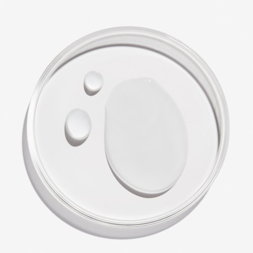 Kolme valkoista nestettä pisaraa läpinäkyvällä lasilautasella, yksi suuri ovaali ja kaksi pienempää ympyräistä.
