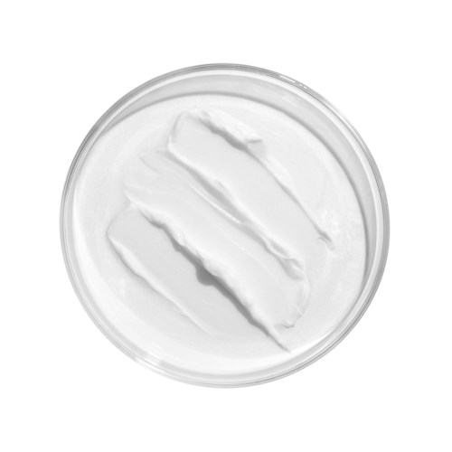 En rund behållare fylld med vit kräm eller lotion med diagonala ränder på toppen.