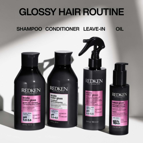 A black bottle of Redken hair gloss with pink label, promoting shine, feel, and heat protection up to 230°C.