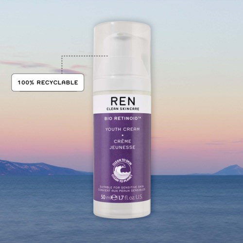 En vit och lila hudvårdsflaska med etiketten REN Bio Retinoid Youth Cream, med en himmel och vattenbakgrund.