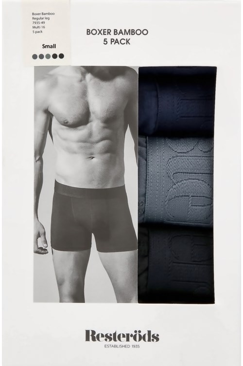 En man med en muskulös överkropp bär svarta boxershorts, med svarta och grå boxerpåsar bredvid honom.