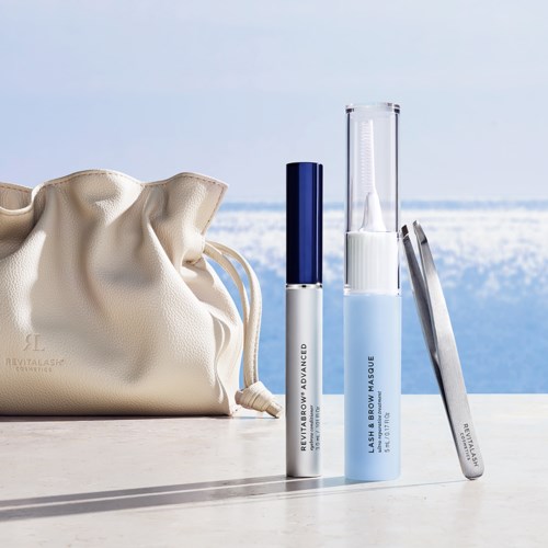 Beauty products with a bag near a coastal background and a set of mascara and eyebrow gel.