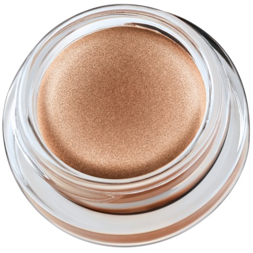 Ett litet glasrör innehåller glänsande, beige färgad kräm eller makeupprodukt. Röran är transparent, visar den släta ytan inuti.