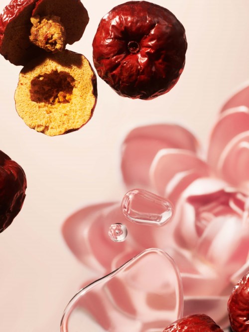 Tørkede kirsebær, et glass og rosa roser er kunstnerisk arrangert på en enkel bakgrunn.