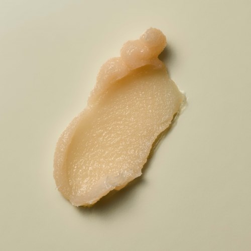 A piece of a pale, creamy substance with a small, irregular top on a light background.