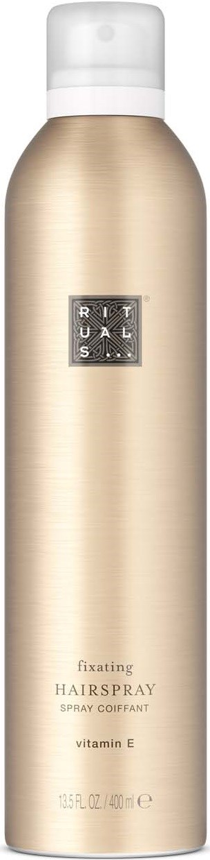 En lang gullfarget sprayflaske med hvit hett, merket Rituals fixeringshairspray med vitamin E.