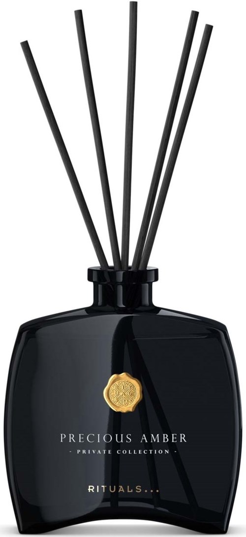 En svart parfyme diffuser-flaske med fem staver og et gullmerke, merket "Precious Amber Rituals."