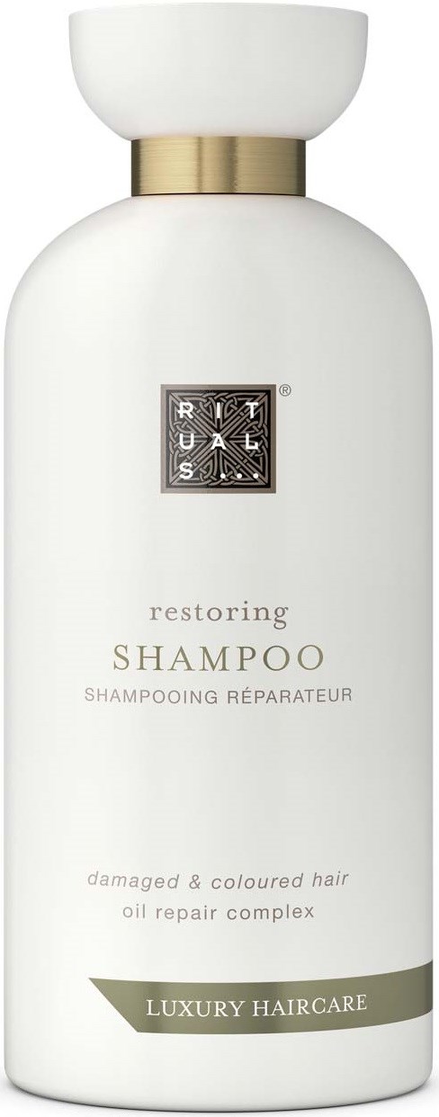 White shampoo bottle with gold band, labeled as restoring shampoo for damaged and colored hair, with luxury haircare branding.