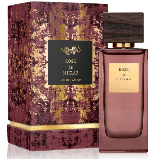 A perfume bottle with a dark wood cap, pinkish liquid, and a decorative box with pink, gold, and black design.