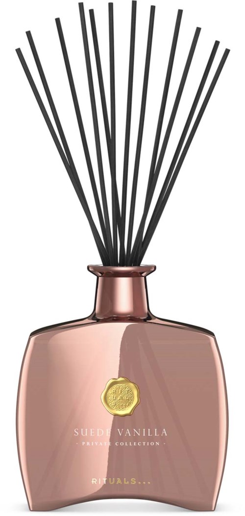En rosa parfymeflaske med svarte reed-stenger og en gullmerke på fronten.