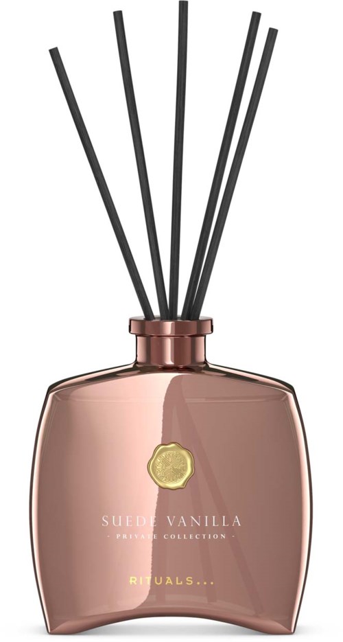 En dekorativ flaske med svarte stk inni, merket Sueen Vanilla og Rituals, rosa gullfarge og buet form.