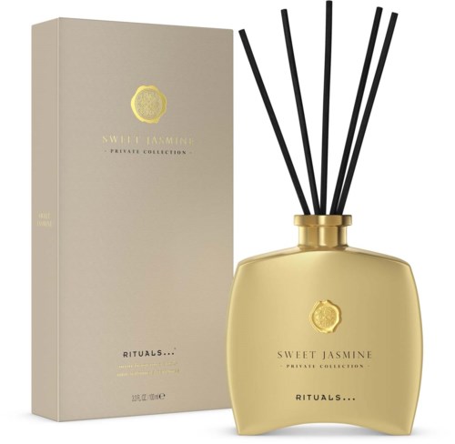 A beige box and gold bottle with black sticks, labeled 'Sweet Jasmine' and 'Rituals' for fragrance.