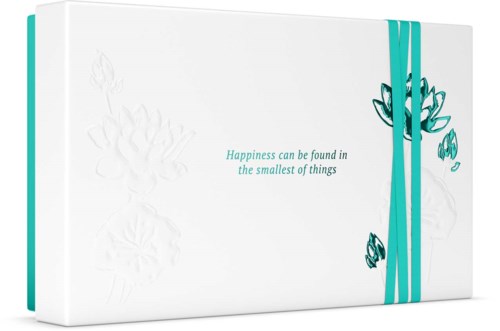 Wit doosje met een tealband en een eenvoudig bloemenontwerp. Tekst zegt: "Happiness can be found in the smallest of things."
