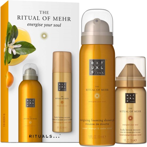 Et sett med gullfargede ritualpleieprodukter, inkludert en skummende dusj, kroppslotion og en liten beholder, med naturlige element.