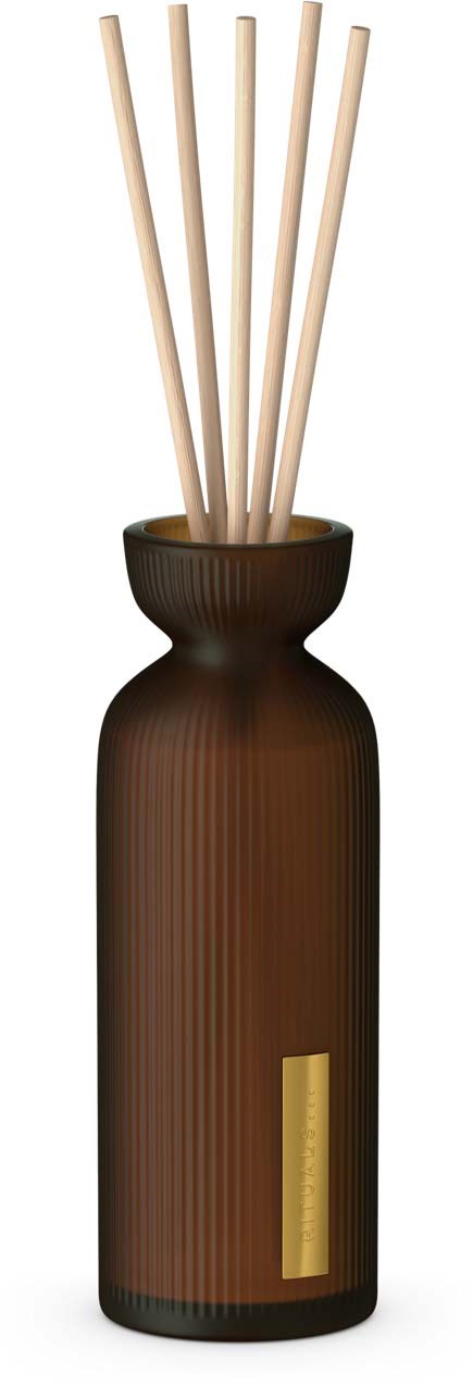 En brun vase holder fem lyse stavrekker, brukt til å spre duft eller luftfrisker.