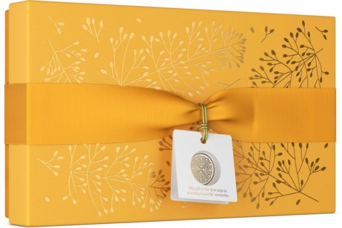 Een gele geschenkdoos met een gele lint, versierd met witte en donkerbruine bladpatronen, en een label hangt eraan.