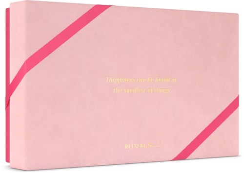 Nattäppellåda med gul text och rosa diagonala ränder, visar ett citat om lycka och ritualer.