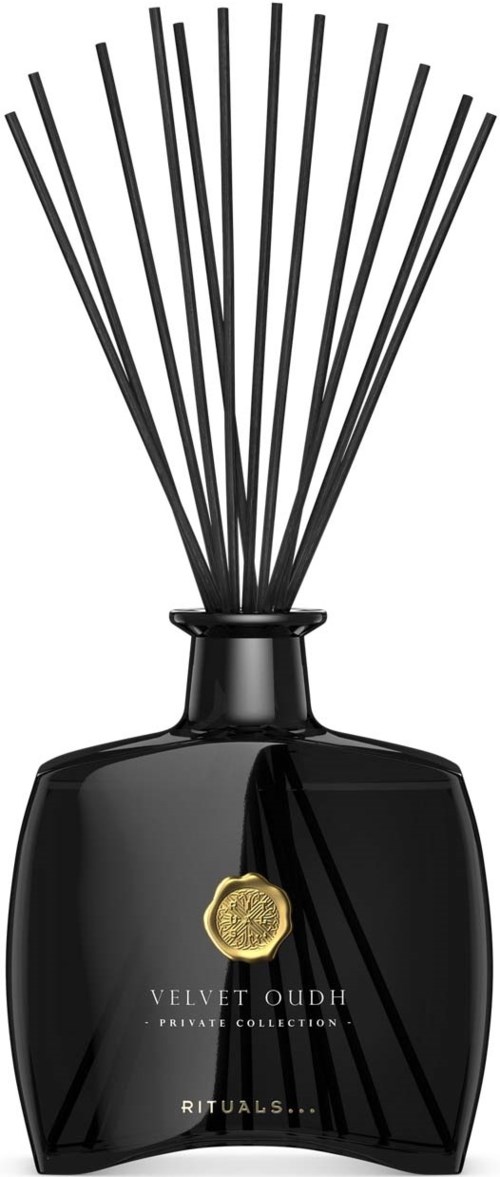 Czarna butelka perfum z czarnymi patyczkami i złotym odznakiem, część kolekcji Velvet Oud.