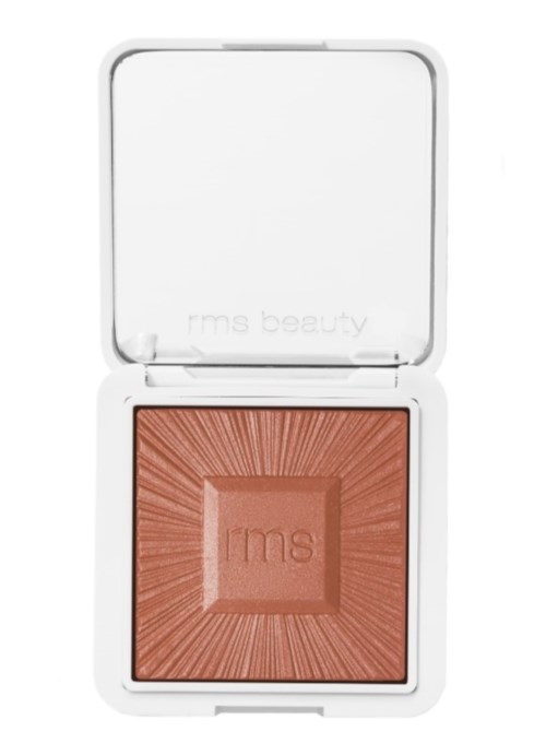 A makeup product in an open white compact with a peach-colored powder inside.