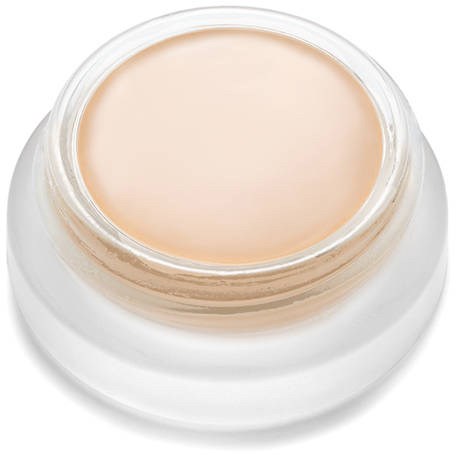 A small jar with beige cream or makeup inside, seen from above, with a white base.