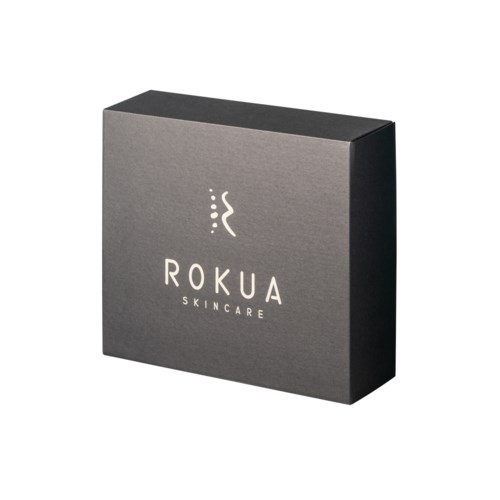 En grå kasse med 'ROKUA SKINCARE' skrevet på den, med en lille abstrakt logo over teksten.