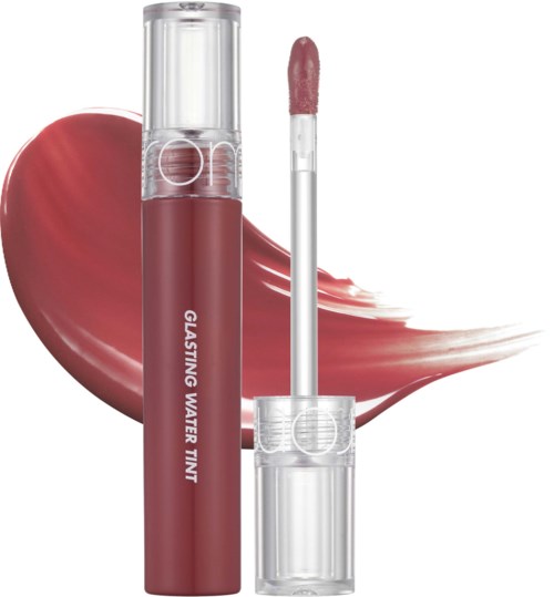 En leppestiftbeholder med applikator, merket 'Glistening Water Tint,' foran et rosa-rødt kosmetisk stryk.