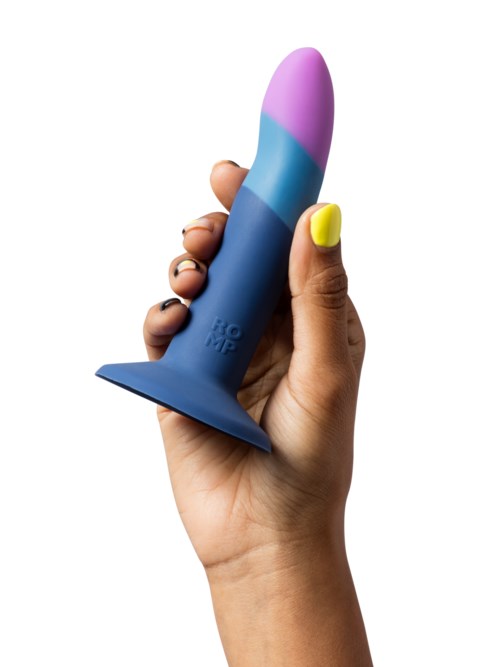 A hand holds a colorful, curved object resembling a toy or sculpture with pastel shades of pink, blue, and purple.