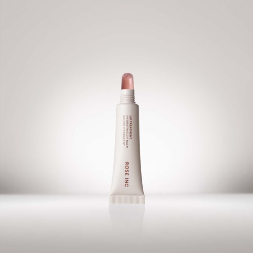 Ein Lippenbalsam in einer Tube steht aufrecht, mit rosa Balsam, Beschriftung liest 'ROSE INC' und Produktbeschreibung.