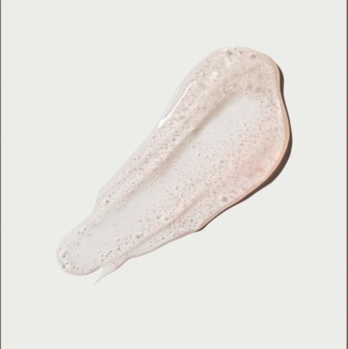En klick ljus rosa kräm eller lotion med skum ovanpå, utbredd på en vit bakgrund.