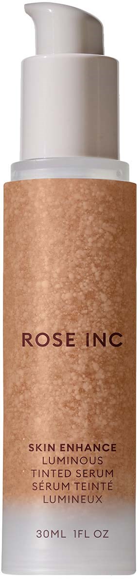 En lång vit flaska med pump, etiketten säger 'ROSE INC' och 'Skin Enhance Luminous Tinted Serum'.