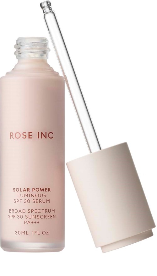 En lyserød flaske mærket 'ROSE INC' med pipette ved siden af en hvid låg. Det er solcreme serum.