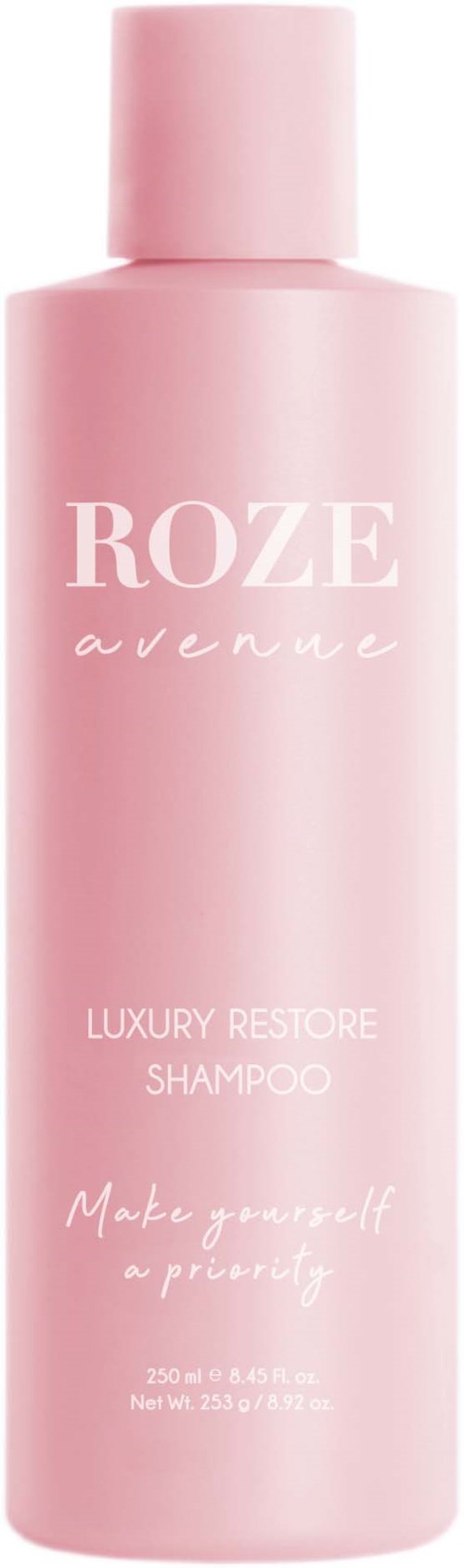 En lang lyserød flaske mærket 'ROZE avenue' til luksus restore-shampoo. Den siger 'Make yourself a priority.'