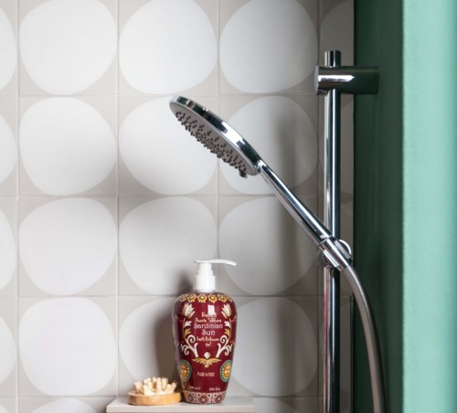 Dusche mit Chrom-Duschkopf, grüner Duschvorhang und dekorative rote Seifenspender an der Wand.