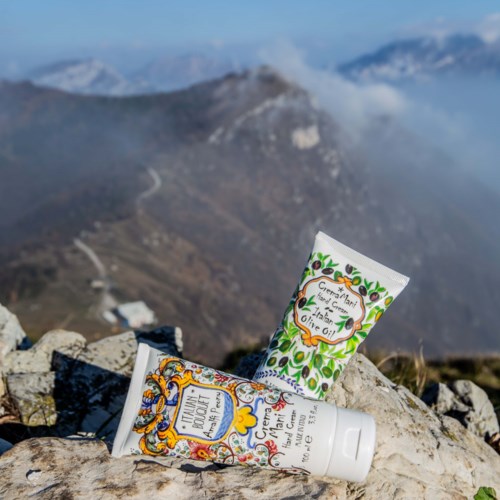 Zwei Tuben Creme auf Steinen mit Berglandschaft im Hintergrund.