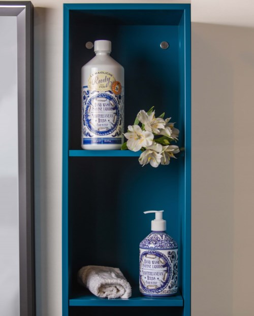 Eine blaue Ablage hält eine weiße Seifenflasche, weiße Blumen und ein Handtuch mit Seifenspender.