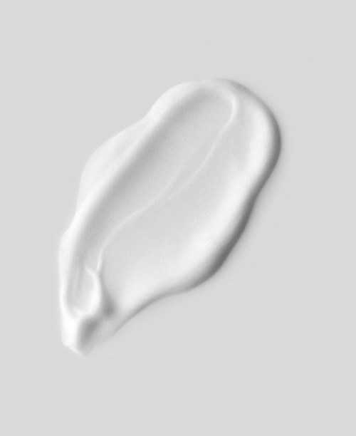 A white, creamy substance spread out on a gray background, shaped like an elongated blob.
