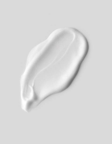 En hvit, kremaktig substans spredt på en grå bakgrunn, muligens lotion eller krem. Jevn og blank tekstur.